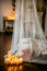 Loft-style room with a bed, a canopy, a white fireplace with a flower arrangement, lit candles, close-up