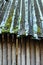 Log cabin with old roofing. Angled roof covered with green moss, snow and icicles