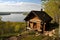 a log cabin perched on a bluff, with a view of the lake below