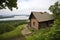 a log cabin perched on a bluff, with a view of the lake below