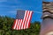 Log cabin roof & American Flag Against a Blue Sky. A red, white and blue American flag with stars and strips unfurled in the wind