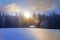 Log cabin window in wintry forest at sunrise