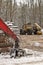 Log or Logging Skidder and Knuckleboom loader with Freshly Harvested and piled timber logs