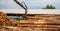 Logging, sawmill. Manipulator for loading wood. The loader of boards and logs works against the background of a stormy sky