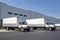 Logistics hub with warehouse building and day cab middle duty semi trucks with box trailers waiting for the next load and local