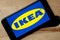 Logo of Ikea on iPhone 11 screen on a wooden bench.