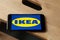 Logo of Ikea on iPhone 11 screen on a wooden bench.