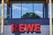 Logo of a supermarket in the surrounding countryside of Berlin, Germany, with blurred reflections of a tree in a big window