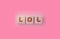 LOL abbreviation for Laughinf Out Loud on Wooden blocks on a sof pink background. Selective focus. Social concept