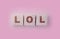 LOL abbreviation for Laughinf Out Loud on Wooden blocks on a sof pink background. Selective focus. Social concept