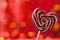 Lollipop on a heart shaped stick on a red background. bokeh