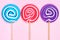 Lollipops in blue, pink and purple colors against pink wood