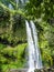 Lombok - A girl standing under Tiu Kelep waterfall