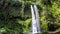 Lombok - A man standing under Tiu Kelep waterfall