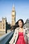 London city travel in Europe woman tourist walking on Westminster Bride at Big Ben. Happy Asian smiling girl wearing