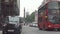 London downtown image with street traffic cars and red double decker buses