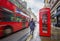 London, England - Iconic blurred red double-decker bus on the move with traditional red telephone box and walking man