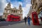 London, England - Tourist couple walking by a traditional red telephone box with red double-decker bus