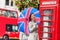 London tourist travel woman with UK flag umbrella, telephone box, red big bus. Europe travel destination Asian girl with