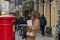 London, UK - 17, December 2018: Woman drop letter in the red color traditional victorian British postbox standing on the London