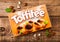 LONDON, UK - APRIL 15, 2019: Box of Toffifee candies on wooden background with meant and nuts. A hazelnut in Caramel with Creamy
