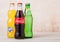 LONDON, UK - AUGUST 03, 2018: Glass bottles of Coca Cola and Fanta and Sprite soft drink on wooden background. Most popular drinks