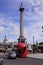 London, UK: red bus passing under the Nelson`s Column in Trafalgar Square.