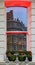 London - Yellow building with bay windows reflected in a window across the street with dramatic red lighting on sills and a window