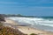 A lone beachcomber on Beverly Beach with Yaquina Head Lighthouse in the background near Newport, Oregon, USA