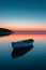 A lone boat drifting on a serene, glassy lake at the break of dawn