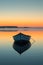 A lone boat drifting on a serene, glassy lake at the break of dawn