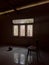 Lone broken chair on tiled floor and near beige colored wall in a empty abandoned dirty house with rubbish and dust on the floor