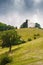 Lone church at the top of a mountain hill. Green meadow with tr