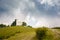 Lone church at the top of a mountain hill. Green meadow with trees. Landscapes of Italy.Cloudy sky.