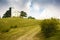 Lone church at the top of a mountain hill. Green meadow with trees. Landscapes of Italy.Cloudy sky.