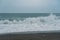 Lone crashing wave on black rocky beachfront