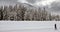 A lone Cross country skier glides across a snow covered alpine landscape.