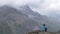 A lone female hiker looks out over some high alpine mountains