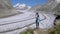 A lone female hiker looks toward a vast glacier.