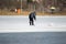 A lone fisherman is bent over a hole in the ice and is trying to catch a fish