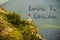 Lone girl standing on outcrop  looking over a deep valley in the mountains with motivational message Dare to Dream