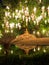 Lone golden Buddha sitting in the lotus position under a large tree