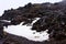 Lone hiker going up a track through the snow blanketed lava fields on the slopes of Mt Ruapehu. Tongariro National Park