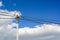 A lone lantern and wires to it on a high pole. A blue spring sky and clouds.