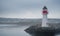 A lone lighthouse atop an outcropping of rock in the Bay of Grand Bank, Newfoundland, on a gray sky, summer morning.