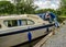 A lone man casting off his boat on the River Bure on the Norfolk Broads, Wroxham, Norfolk, UK