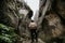 A lone man hiker stands in the mountains between two high cliffs. Extreme summer vacation