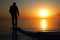 A lone man stands on the seashore during dawn. Beautiful view of the sea and the sun