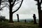 A lone moody hooded figure standing on a hillside, looking out across the English countryside in winter