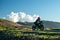 Lone motorcycle riding along a mountain ridge with spectacular landscape and clouds